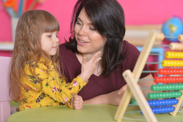 Feche o retrato da mãe ensinando a filha a usar o ábaco