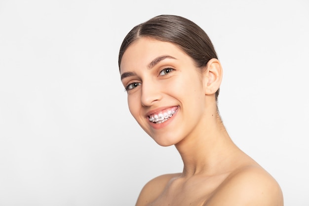 Feche o retrato da menina adolescente sorridente mostrando o aparelho dentário. Isolado no fundo branco.