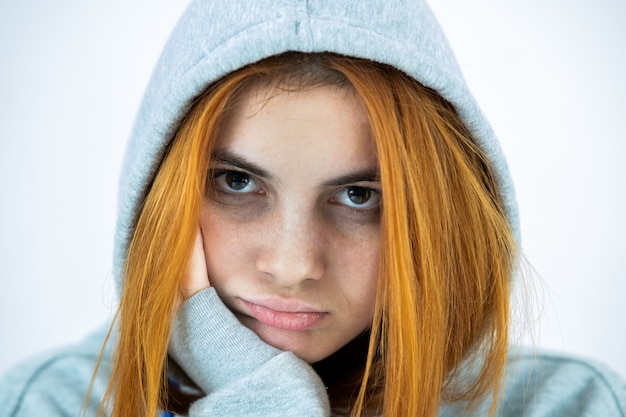 Feche o retrato da mulher triste deprimida jovem ruiva vestindo pulôver quente com capuz.