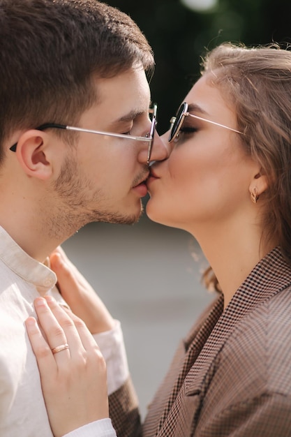 Feche o retrato de duas pessoas se beijando ao ar livre Lindo casal de homem bonito e jovem atraente com cabelo encaracolado Vista lateral