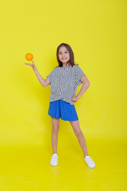 Feche o retrato de estúdio de criança sorrindo, segurando uma laranja.