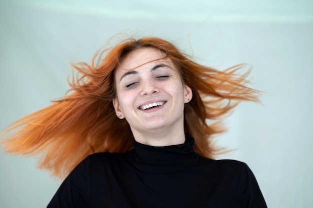 Feche o retrato de menina ruiva bonita com cabelos longos ondulados ao vento.