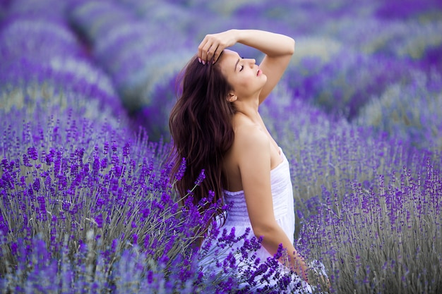 Feche o retrato de mulher jovem e bonita no campo de lavanda.