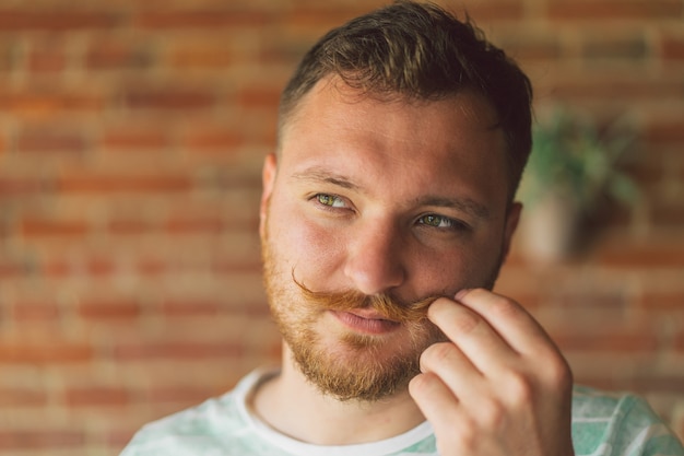 Feche o retrato de um cara bonito e viril com barba e bigode olhando para a câmera e sorrindo alegremente