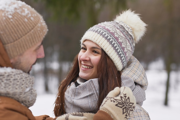 Feche o retrato de um casal adulto feliz ao ar livre no inverno com uma mulher sorridente, olhando para o marido, copie o espaço