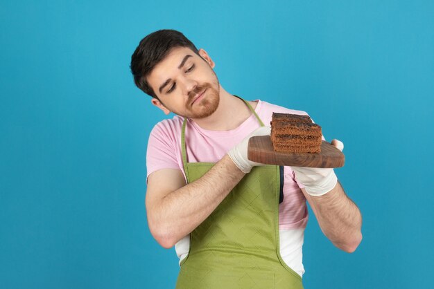 / Feche o retrato de um homem bonito segurando fatias de bolo de chocolate.