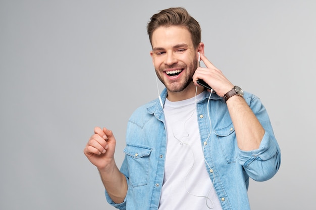 Feche o retrato de um jovem alegre curtindo música, usando uma roupa casual de jeans