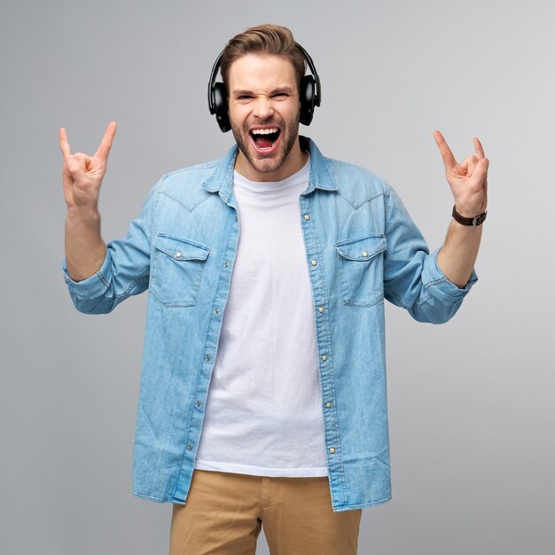 Feche o retrato de um jovem alegre curtindo música, usando uma roupa casual de jeans