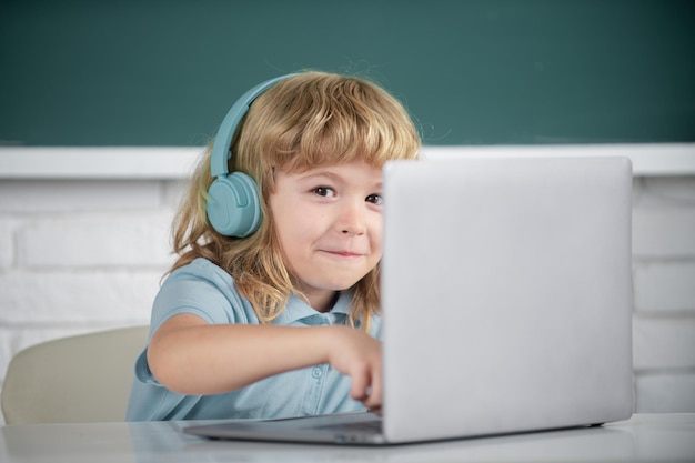 Feche o retrato de um menino em fones de ouvido assista a uma aula de vídeo no computador na escola no ouvido