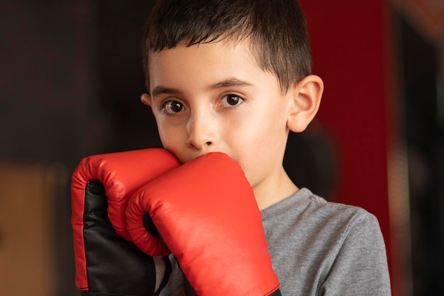 Feche o retrato de um menino usando luvas de boxe vermelhas