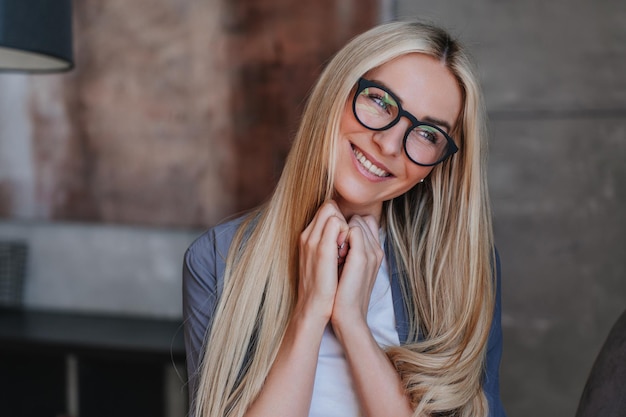 Feche o retrato de uma adorável jovem loira sueca em óculos sorrindo dentuço olha de lado