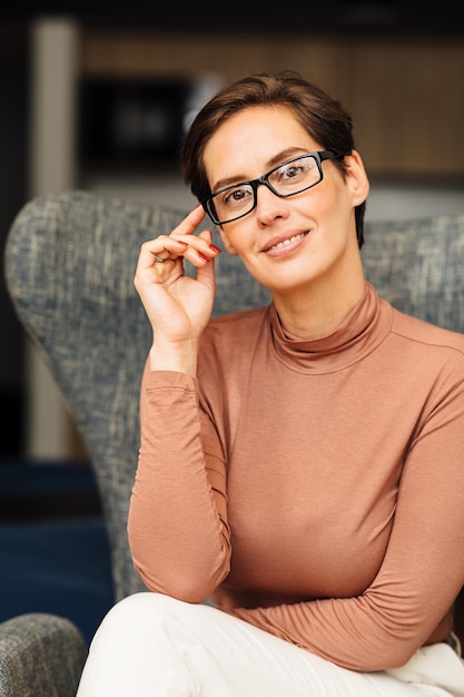 Foto feche o retrato de uma bela empresária sentada em uma poltrona no apartamento