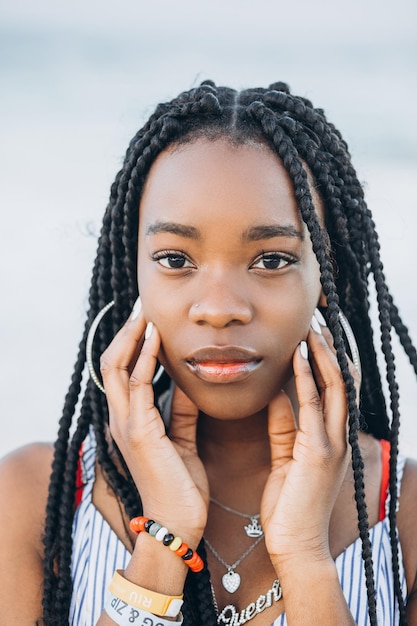 Feche o retrato de uma bela jovem africana perto de palmeiras na praia