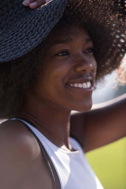 Feche o retrato de uma bela jovem afro-americana sorrindo e olhando para cima em um lindo dia ensolarado