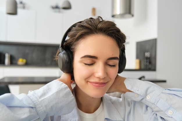 Feche o retrato de uma garota com fones de ouvido que gosta de ouvir música, feche os olhos e os sorrisos formam alegria e