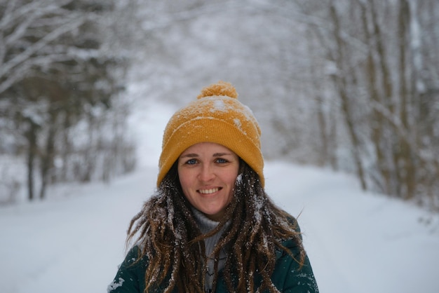 Feche o retrato de uma jovem e bonita mulher caucasiana sorridente contra o fundo da floresta de inverno nevado