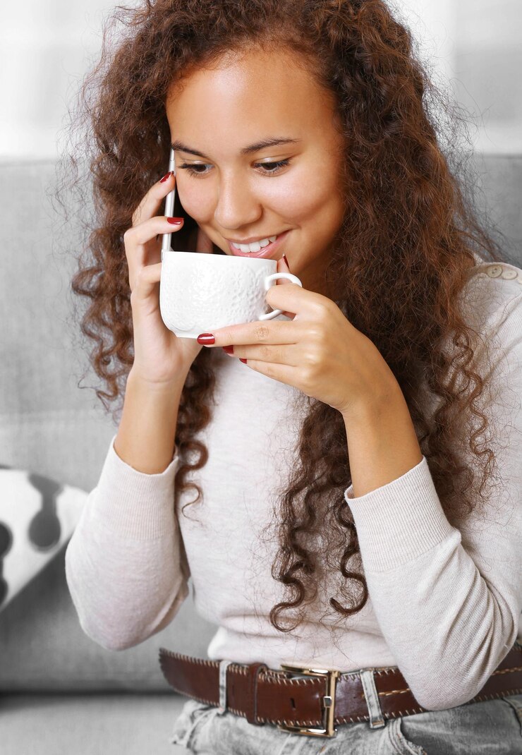 Foto feche o retrato de uma jovem falando ao celular com uma xícara de café na sala
