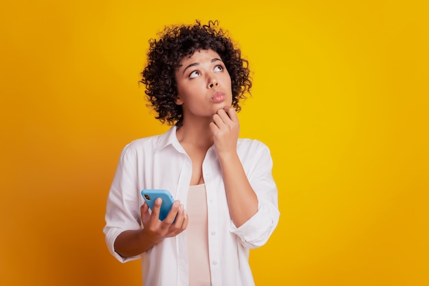 Foto feche o retrato de uma jovem mulher afro-americana. segure o telefone, conversando, procure, pense.