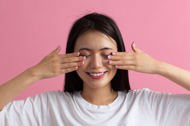 Feche o retrato de uma jovem mulher asiática fazendo massagem facial de reconstrução facial.