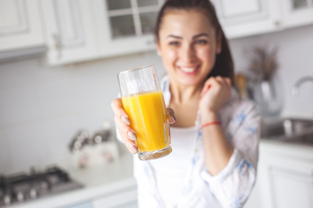 Feche o retrato de uma jovem mulher atraente, bebendo suco fresco