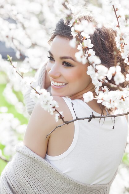 Feche o retrato de uma jovem mulher bonita na primavera. Garota jovem e atraente com flores. Modelo de maquiagem de primavera.