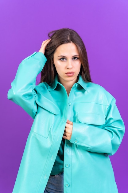 Feche o retrato de uma jovem mulher caucasiana com casaco azul isolado em fundo roxo olhando para a câmera