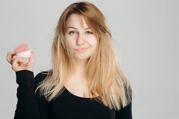 Feche o retrato de uma jovem mulher confusa com cabelo loiro desarrumado