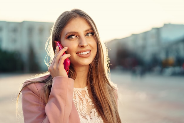 Feche o retrato de uma jovem mulher falando em seu telefone na rua