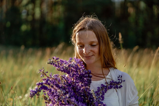 Feche o retrato de uma jovem ruiva linda com sardas usando vestido branco posando na natureza Garota de cabelo vermelho segurando flores Beleza natural Diversidade singularidade individual