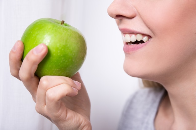 Feche o retrato de uma jovem sorridente comendo maçã verde