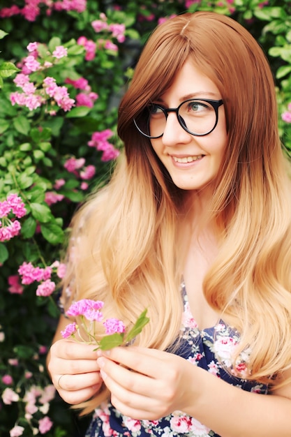 Feche o retrato de uma linda garota em um vestido vintage em pé perto de flores coloridas