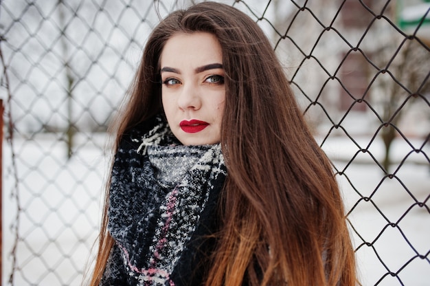 Feche o retrato de uma menina morena com lenço contra a gaiola.