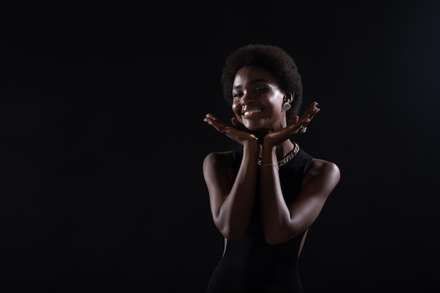 Feche o retrato de uma mulher afro-americana com um penteado afro em fundo preto do estúdio.