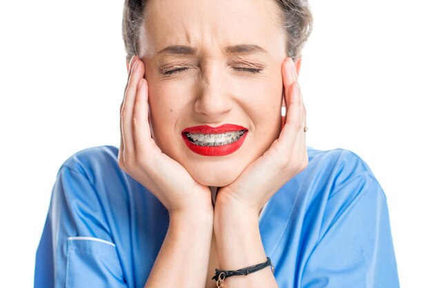 Foto feche o retrato de uma mulher com aparelho dentário no fundo branco. mulher preocupada com um novo sorriso com aparelho