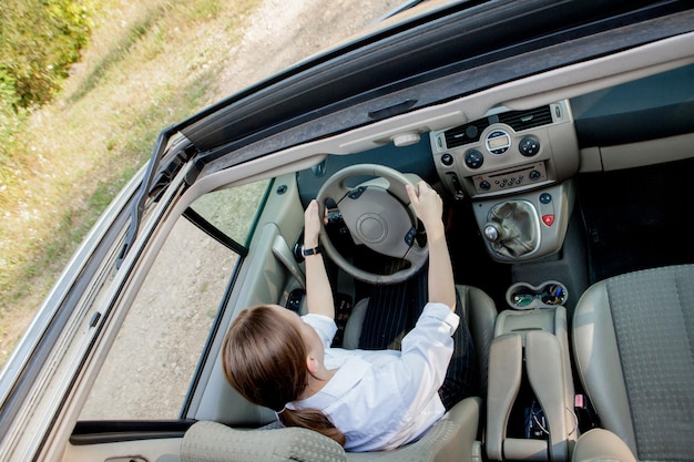 Feche o retrato de uma mulher de aparência agradável com expressão positiva feliz, satisfeita com a viagem inesquecível de carro, senta-se no banco do motorista Pessoas dirigindo o conceito de transporte