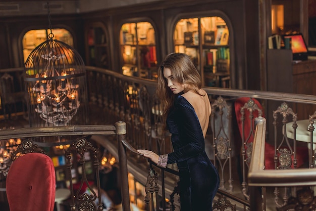 Feche o retrato de uma mulher elegante e luxuosa em um vestido de festa de lantejoulas dourado elegante Penteado ondulado elegante maquiagem brilhante lábios vermelhos Segurando bolsa de noite na moda