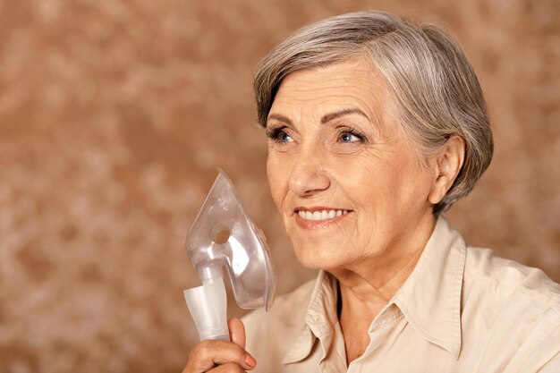 Feche o retrato de uma mulher idosa com inalação de gripe