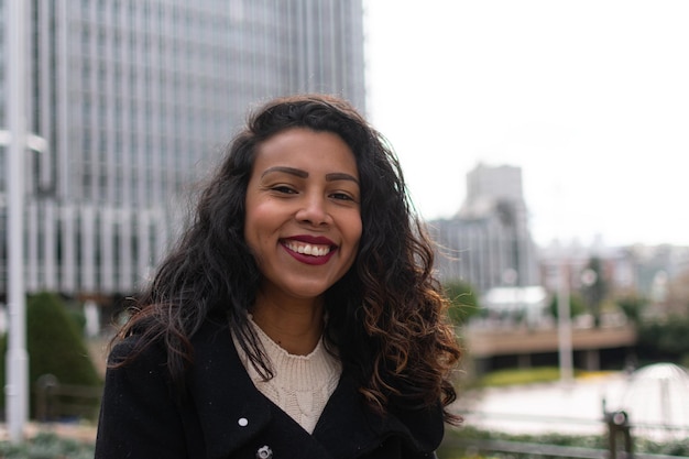 Feche o retrato de uma mulher latina com cabelo encaracolado posando do lado de fora