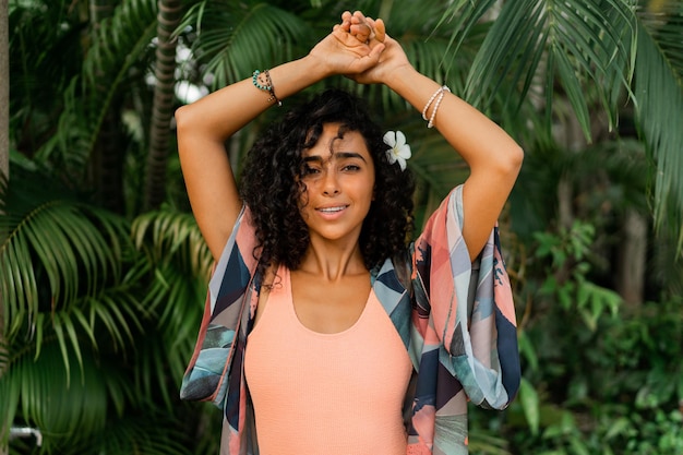 Feche o retrato de uma mulher sorridente com flor de plumeria em cabelos depois de spa em resort de luxo Vestindo roupa tropical boho