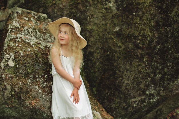 Feche o retrato do assento de menina ucraniana de 7 anos em pedra na floresta