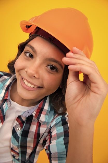 Feche o retrato do construtor de crianças no capacete Adolescente em trabalhos de reparação isolados em fundo amarelo Conceito de renovação de crianças