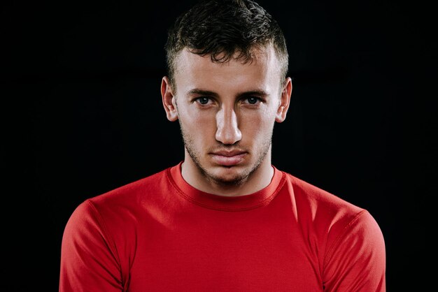 Feche o retrato do desportista caucasiano bonito vestindo roupas esportivas vermelhas e posando após exercícios em fundo escuro Motivação de esporte de estilo de vida de fitness inspirador saudável