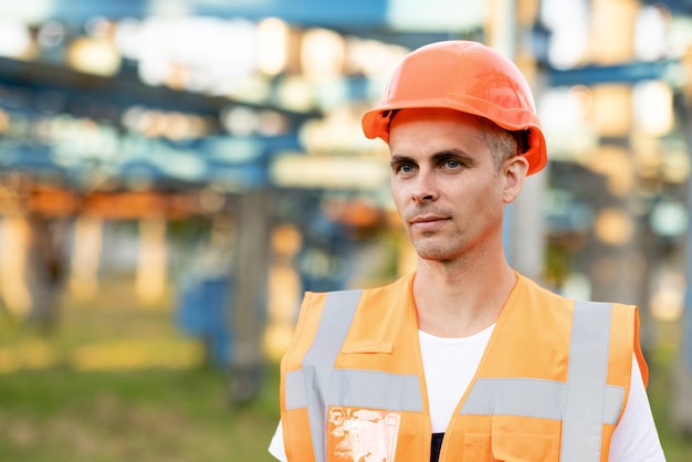 Feche o retrato do engenheiro de uniforme e capacete ao ar livre. Homem trabalhador em pé