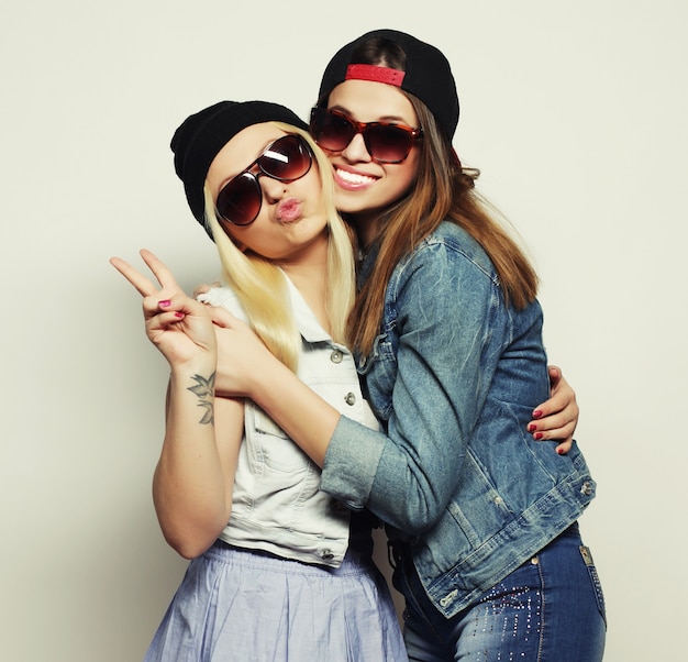 Feche o retrato do estilo de vida de duas namoradas muito adolescentes sorrindo e se divertindo, vestindo roupas hipster e chapéus, humor positivo.