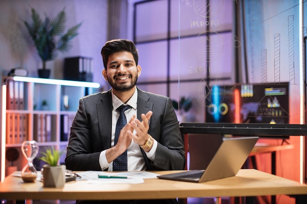 Feche o retrato do trabalhador de escritório especialista financeiro indiano confiante sentado à mesa em traje formal