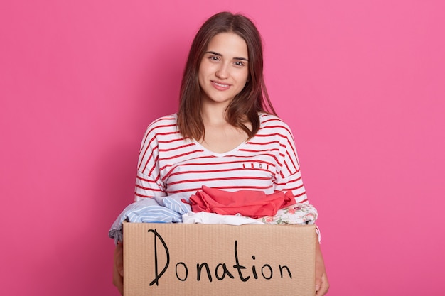 Foto feche o retrato do voluntário sorridente da menina segurando a caixa de papel com roupas para pessoas pobres, senhora fazendo doação