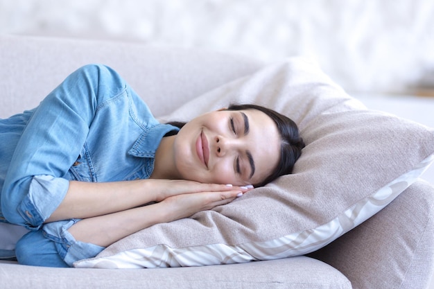 Feche o retrato fotográfico de uma jovem linda dormindo no sofá sorrindo através do sono cansado