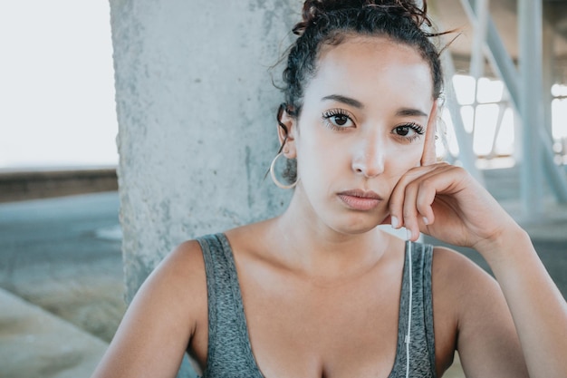 Feche o retrato procurando uma jovem africana séria, fazendo uma pausa após os exercícios de treino. atleta feminina no sportswear relaxar ouvindo música em seu telefone. Esporte urbano. Roupa e top de leggings.