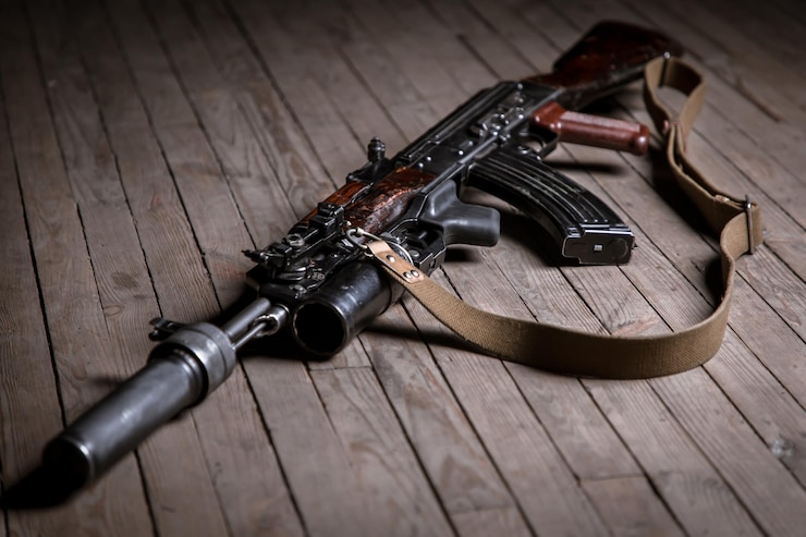 Foto feche o rifle de assalto kalashnikov isolado com supressor em fundo de madeira