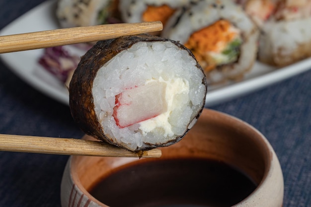 Feche o rolo de sushi com pauzinhos com pauzinhos e soja